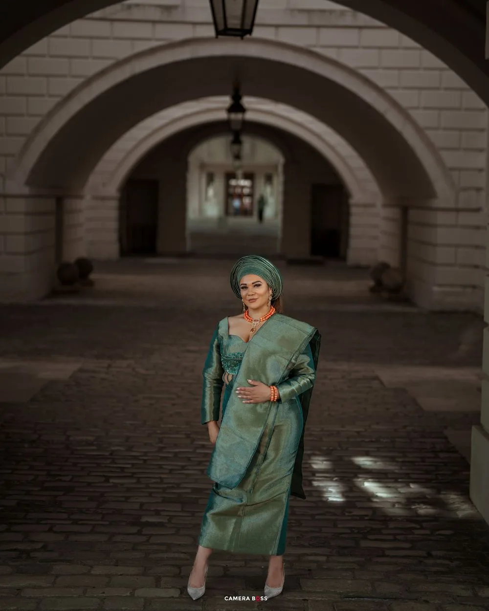 Fashion portrait session in a historic courtyard with arched columns and cobblestone flooring.