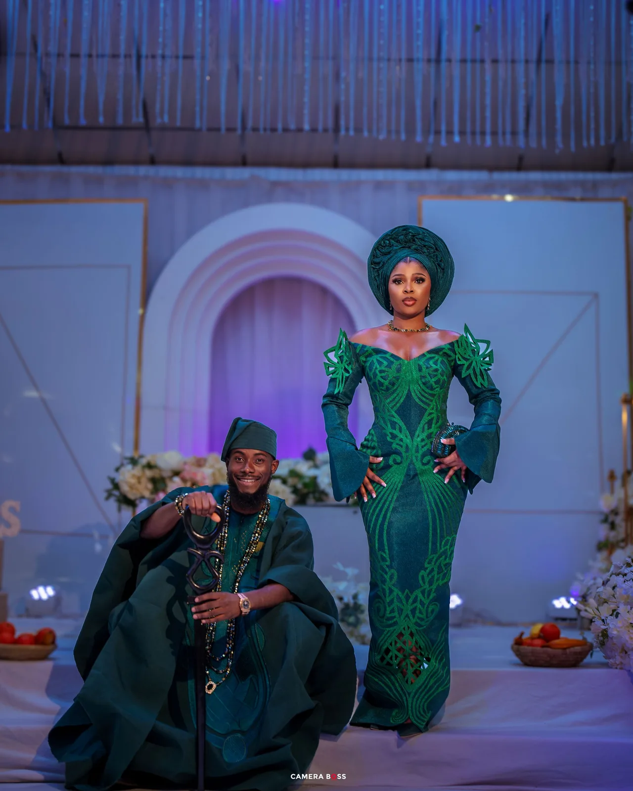 Couple in matching emerald green and black formal attire pose together during a special celebration event.