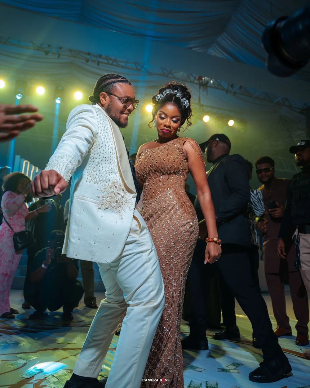 Elegantly dressed couple dancing together at a formal celebration with mood lighting and decorative floor patterns.