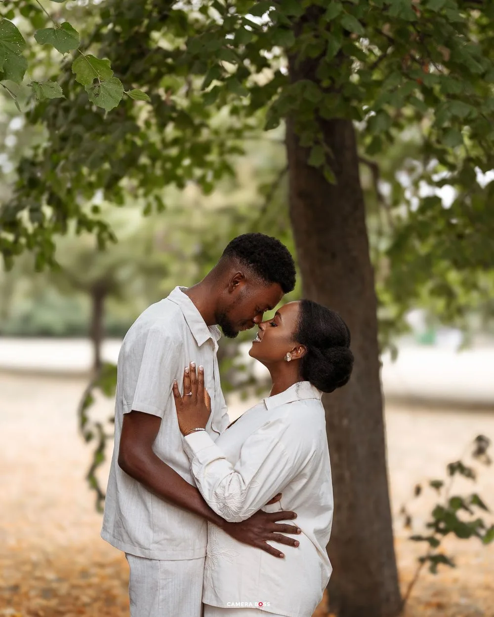 A romantic engagement photoshoot sequence under trees showing a couple in white outfits embracing each other.