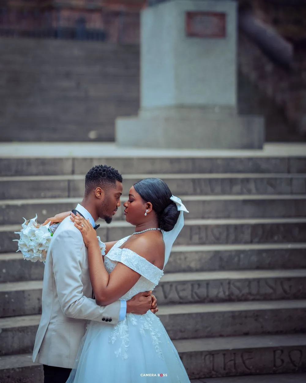 A romantic wedding moment captured on stone steps with gothic architecture in the background.