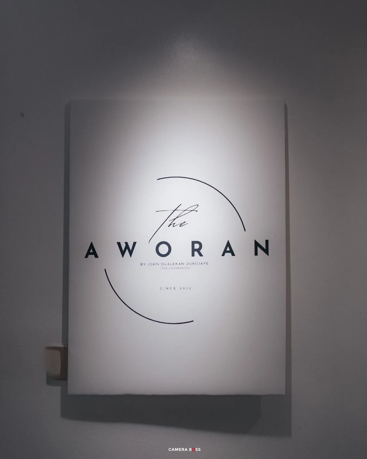 A modern minimalist logo for a restaurant named 'Aworan' mounted on a white wall with dramatic lighting.