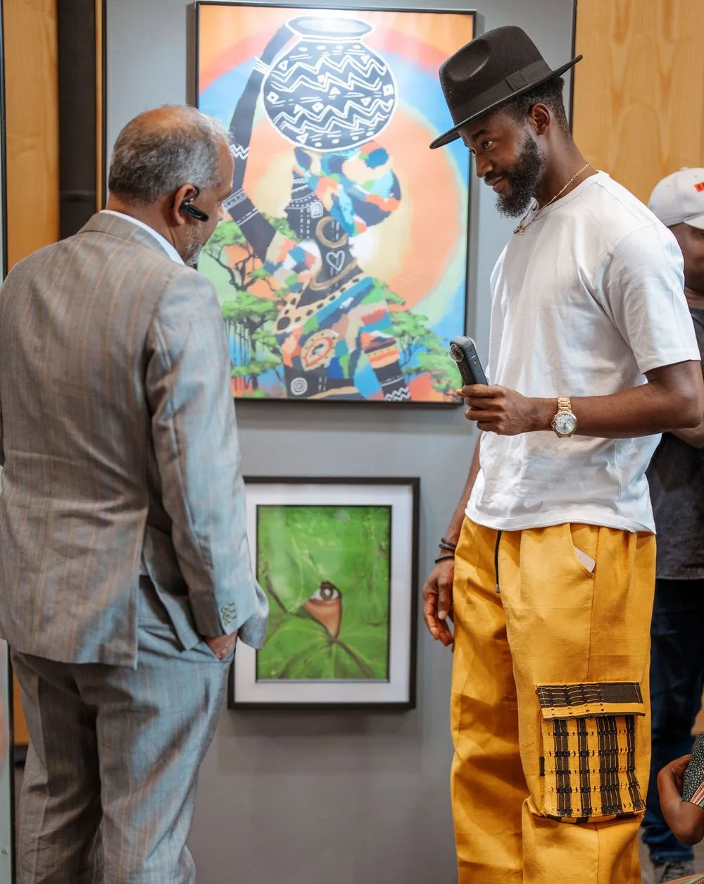 Two men viewing colorful African-inspired artwork at an art gallery exhibition.