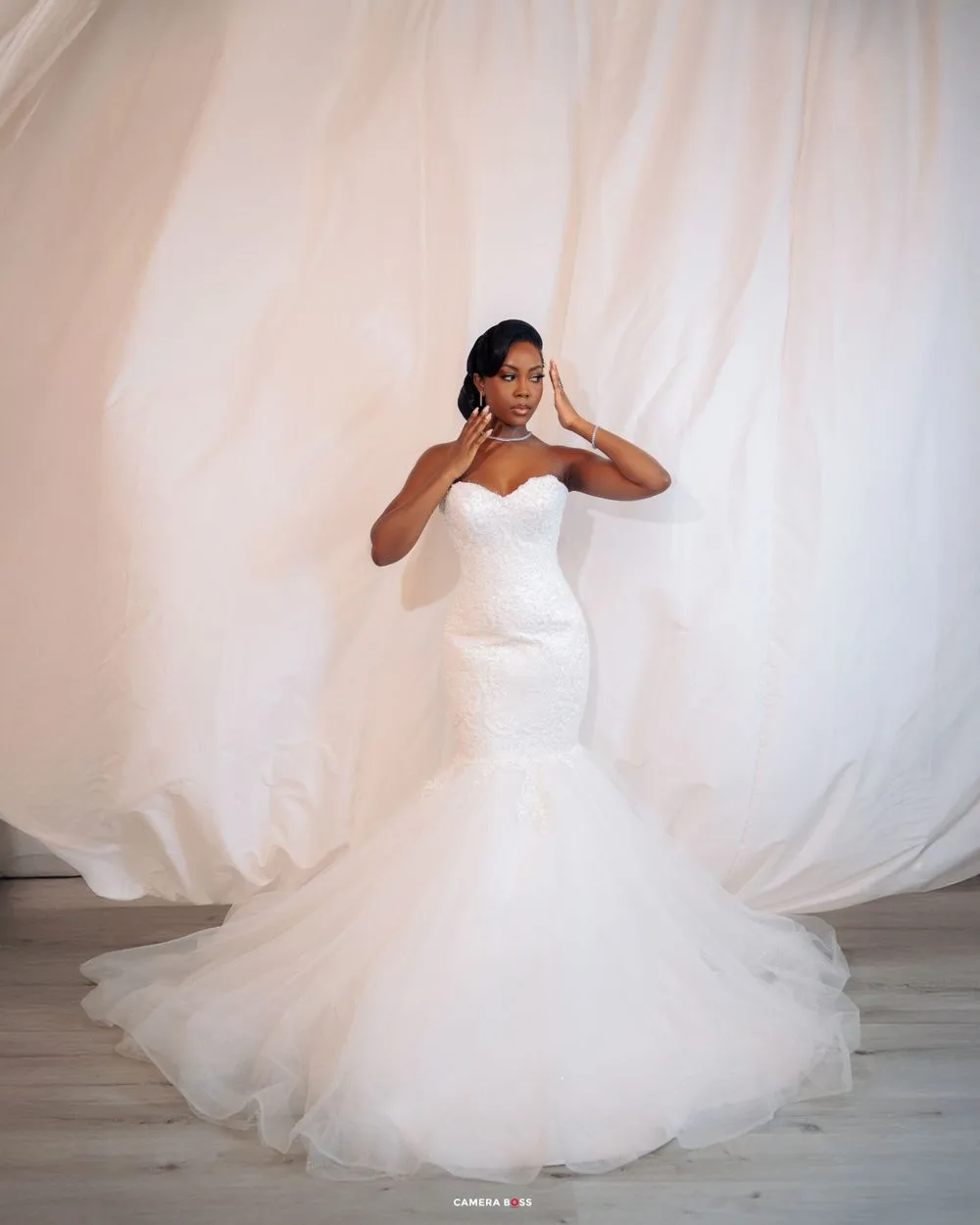 A stunning mermaid-style wedding dress with a strapless sweetheart neckline and flowing tulle skirt against a white backdrop.
