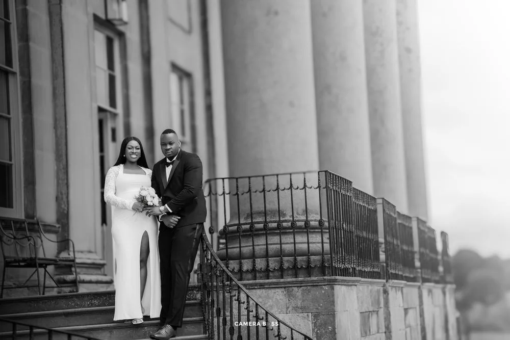 A black and white wedding photo of a couple standing on the steps of a grand building with elegant columns.