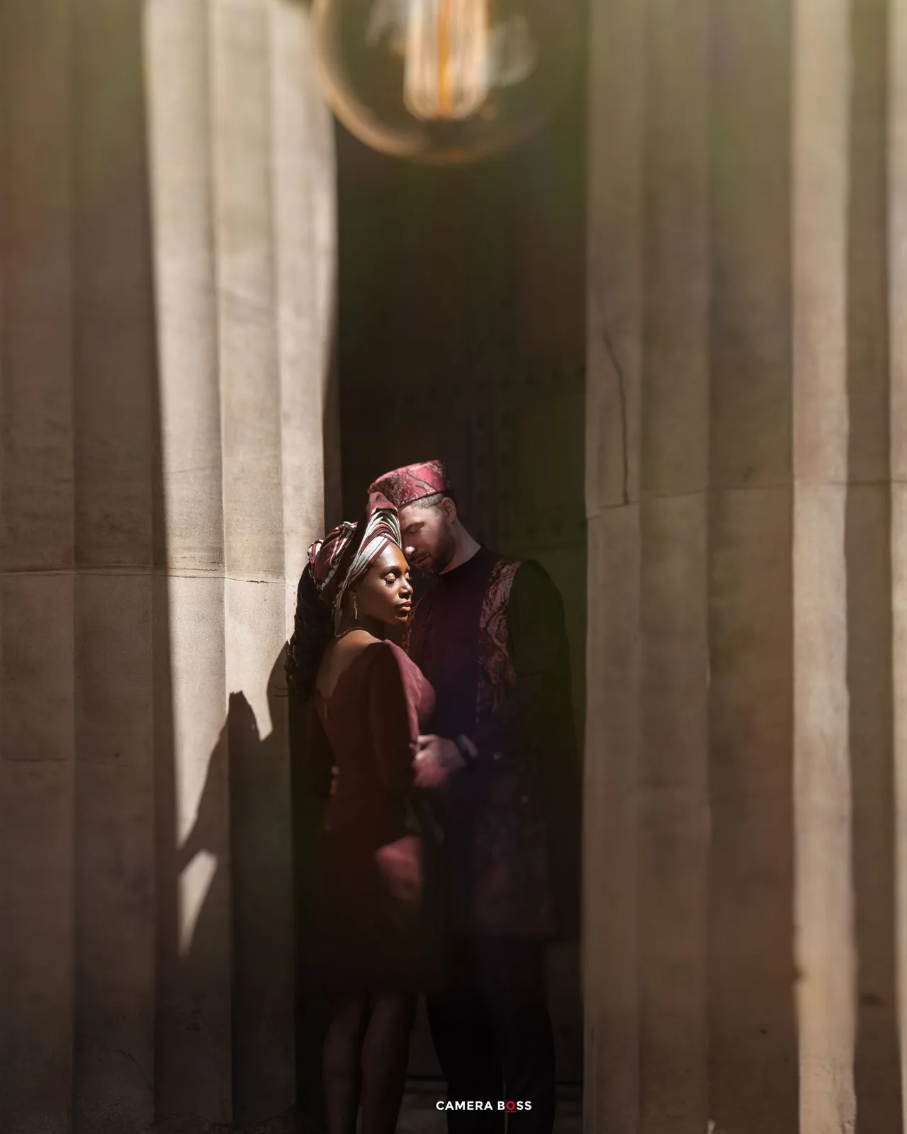 A silhouetted couple embraces among illuminated white columns creating a romantic architectural composition.