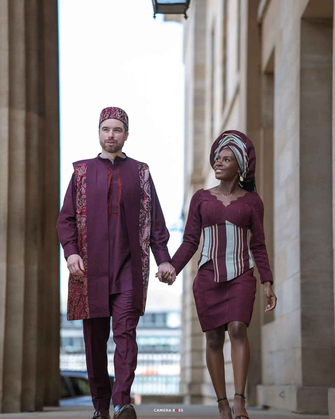 Fashion models showcase burgundy athletic wear collection with striped details in an elegant colonnade setting.