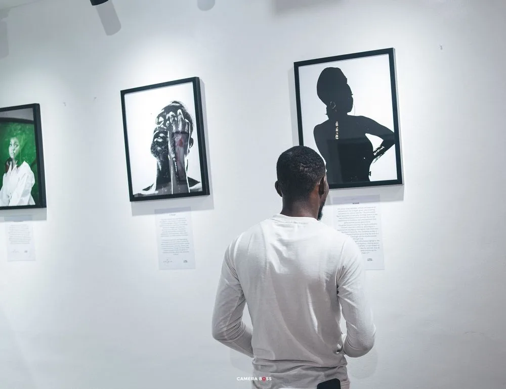 A person in a white shirt views black and white portrait photographs displayed on a gallery wall.