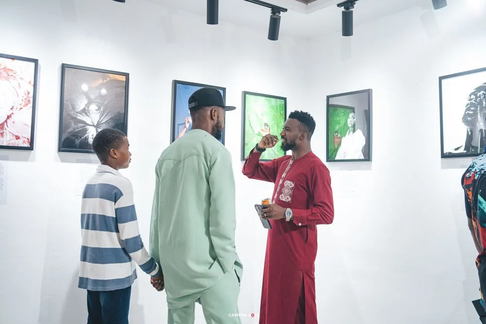 People viewing artwork displayed in a modern gallery with white walls and framed portraits hanging.