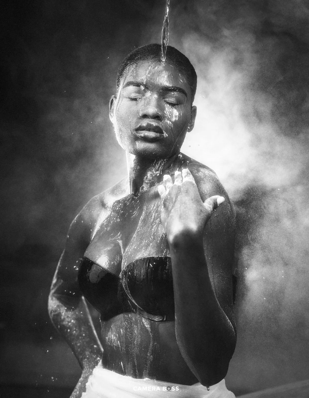 Artistic black and white portrait of a person under water with dramatic steam and lighting effects against dark background.