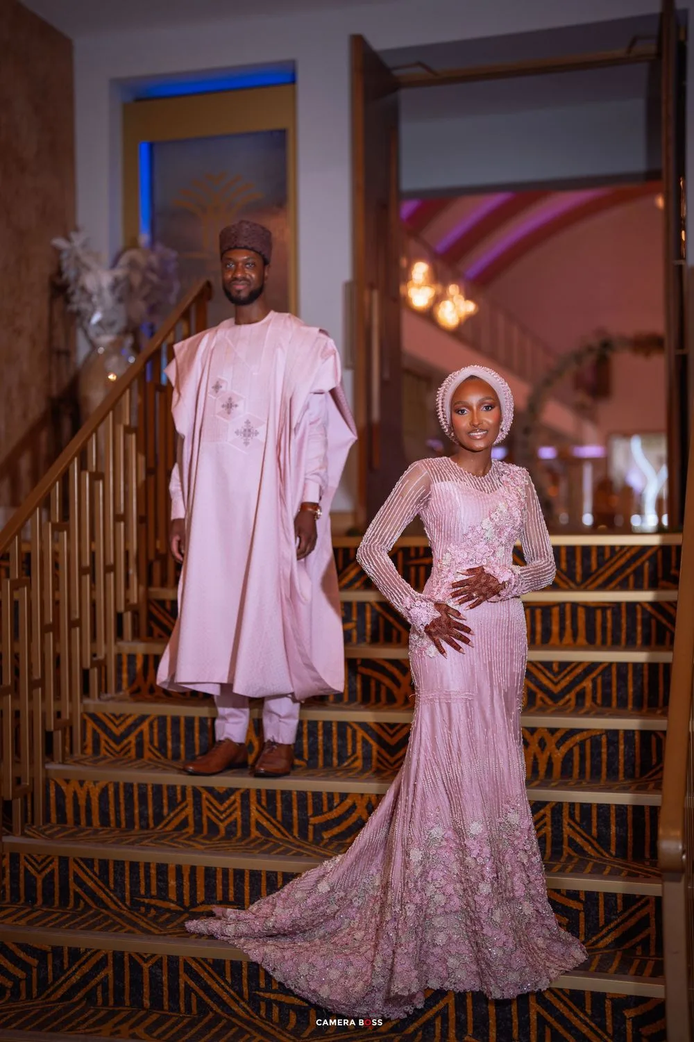 Wedding fashion photoshoot featuring elegant white traditional outfits with intricate embroidery details against wooden railing.
