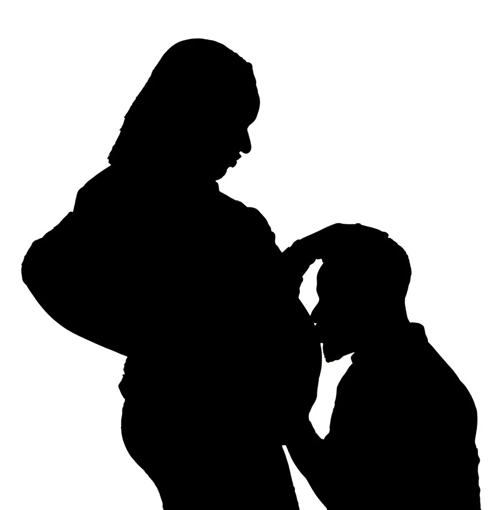 A silhouetted pregnant woman and child in tender interaction against a white background.