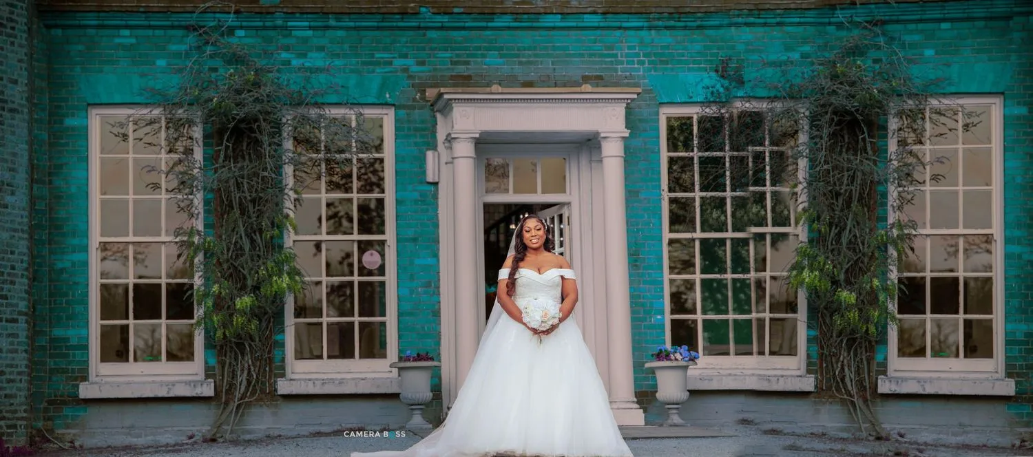 A person in a white wedding gown poses in a doorway framed by turquoise walls and climbing vines.