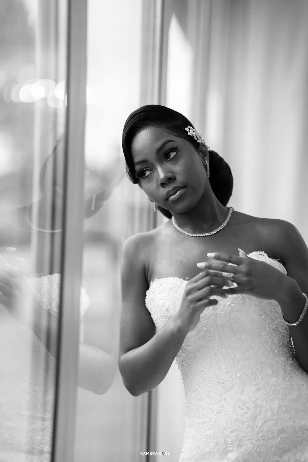 A bride wearing a classic white wedding dress poses elegantly in black and white photography.