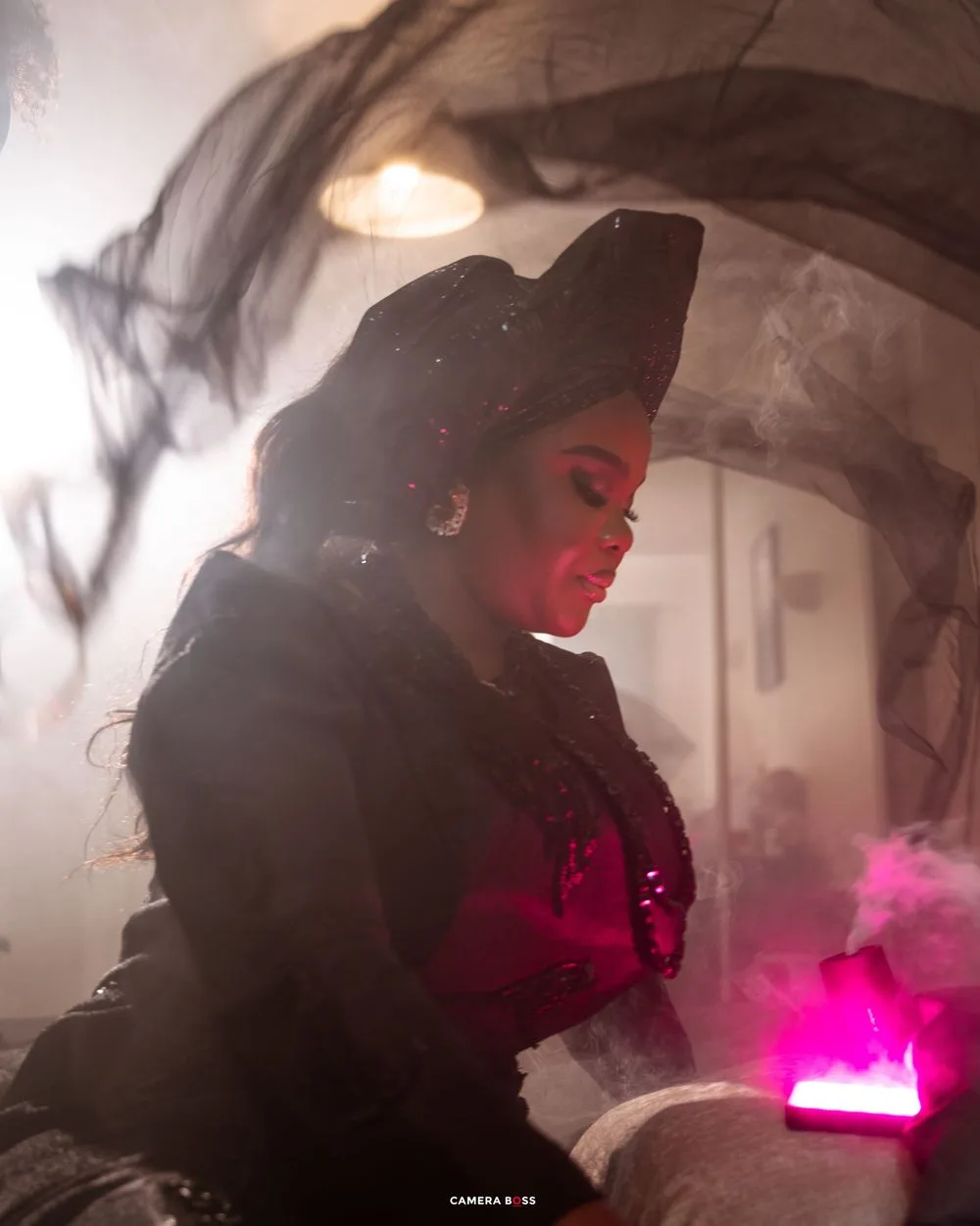 A figure in dark clothing illuminated by ethereal pink light and fog creates a moody atmospheric scene.