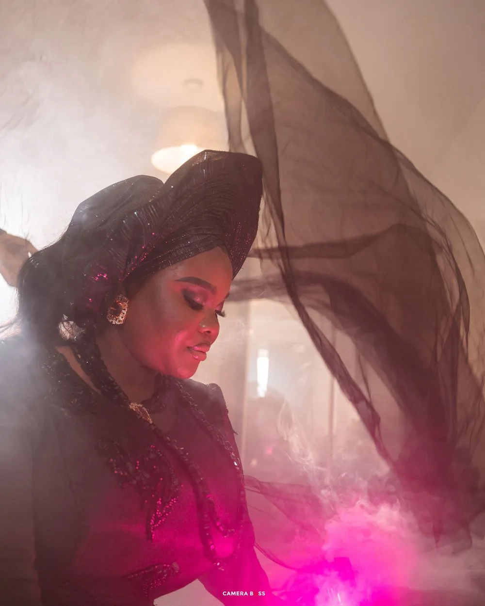 Artistic portrait with flowing black veil and dramatic pink lighting creates ethereal mood.