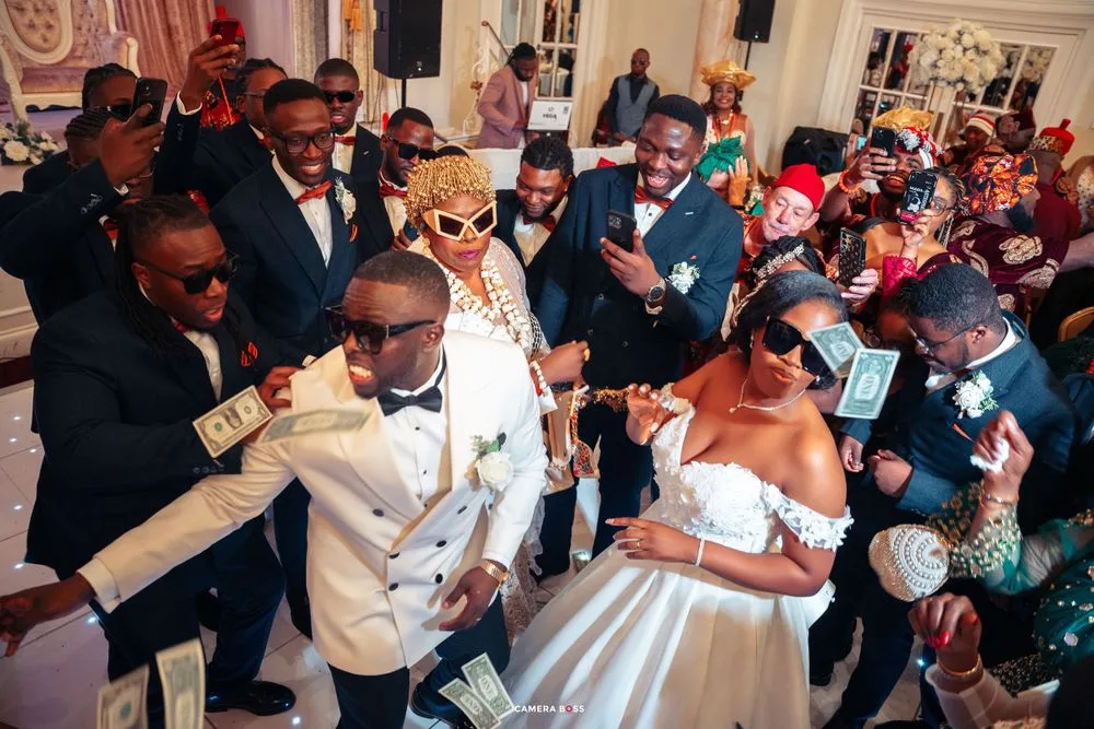Joyful wedding celebration with guests dancing and cheering in an elegant ballroom setting.