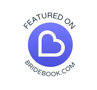 A circular blue badge featuring a heart outline and text 'Featured on Bridebook.com' arranged around the perimeter.