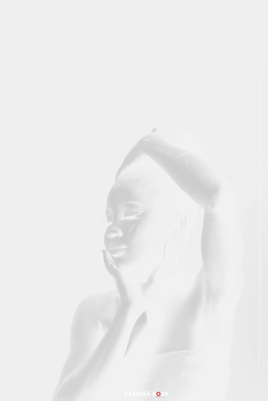 High-key monochromatic portrait in ethereal white tones showing a serene expression against light background.