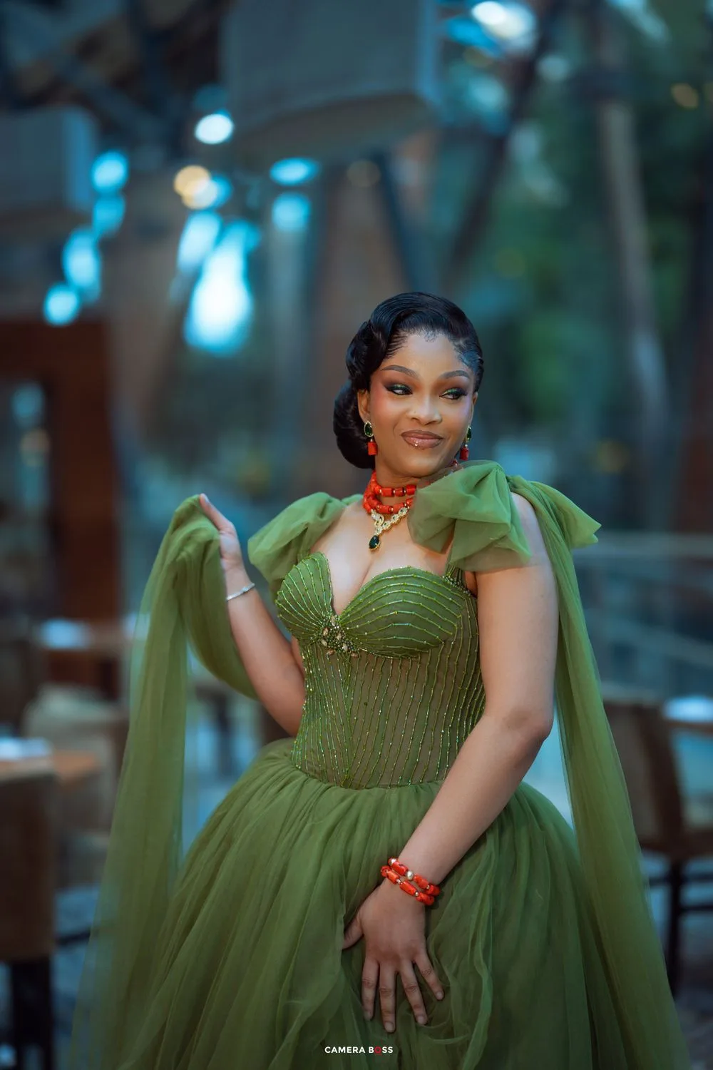 Elegant evening photoshoot featuring a flowing olive green corset gown with statement bow details and red accessories.