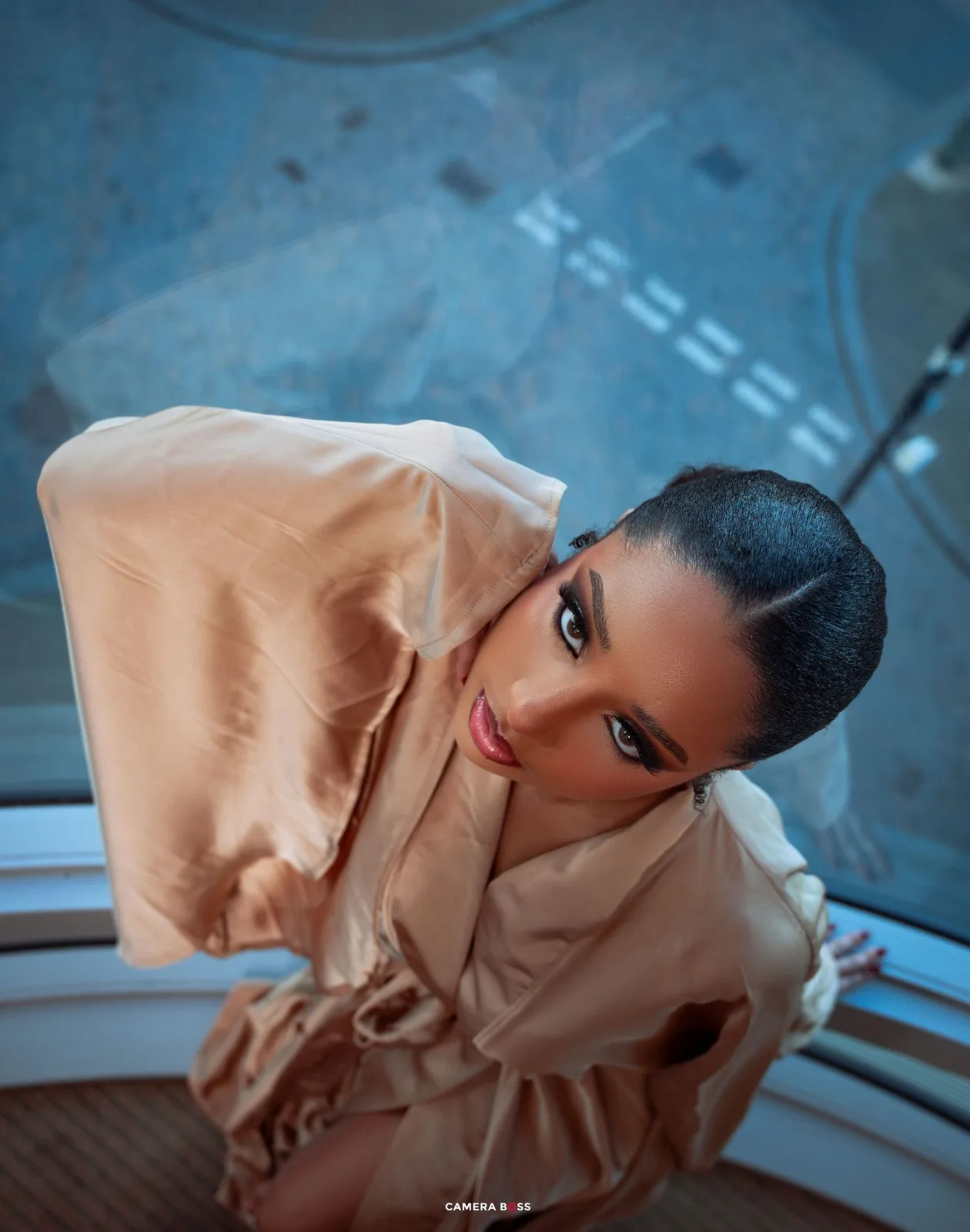 Looking down at figure in peach-colored outfit against blue background with dramatic aerial perspective.