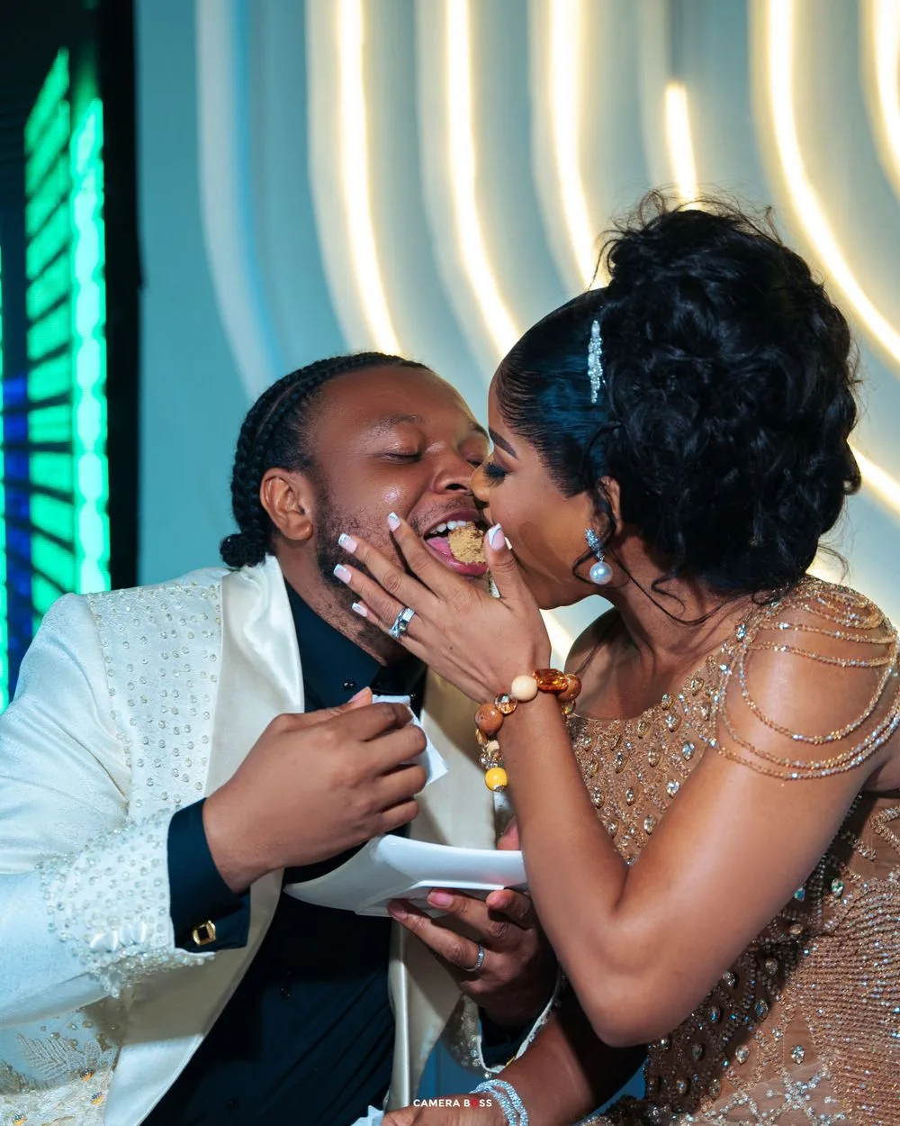 A joyful couple shares an intimate moment at their wedding reception, both dressed in formal evening attire.