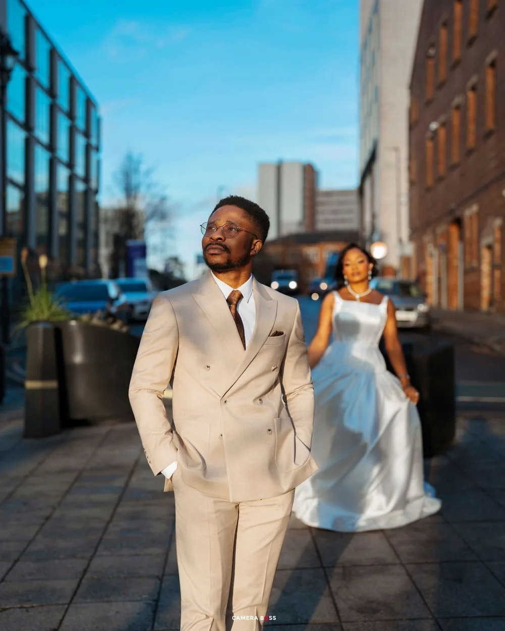 A joyful couple in formal attire dances together on a city rooftop during sunset.