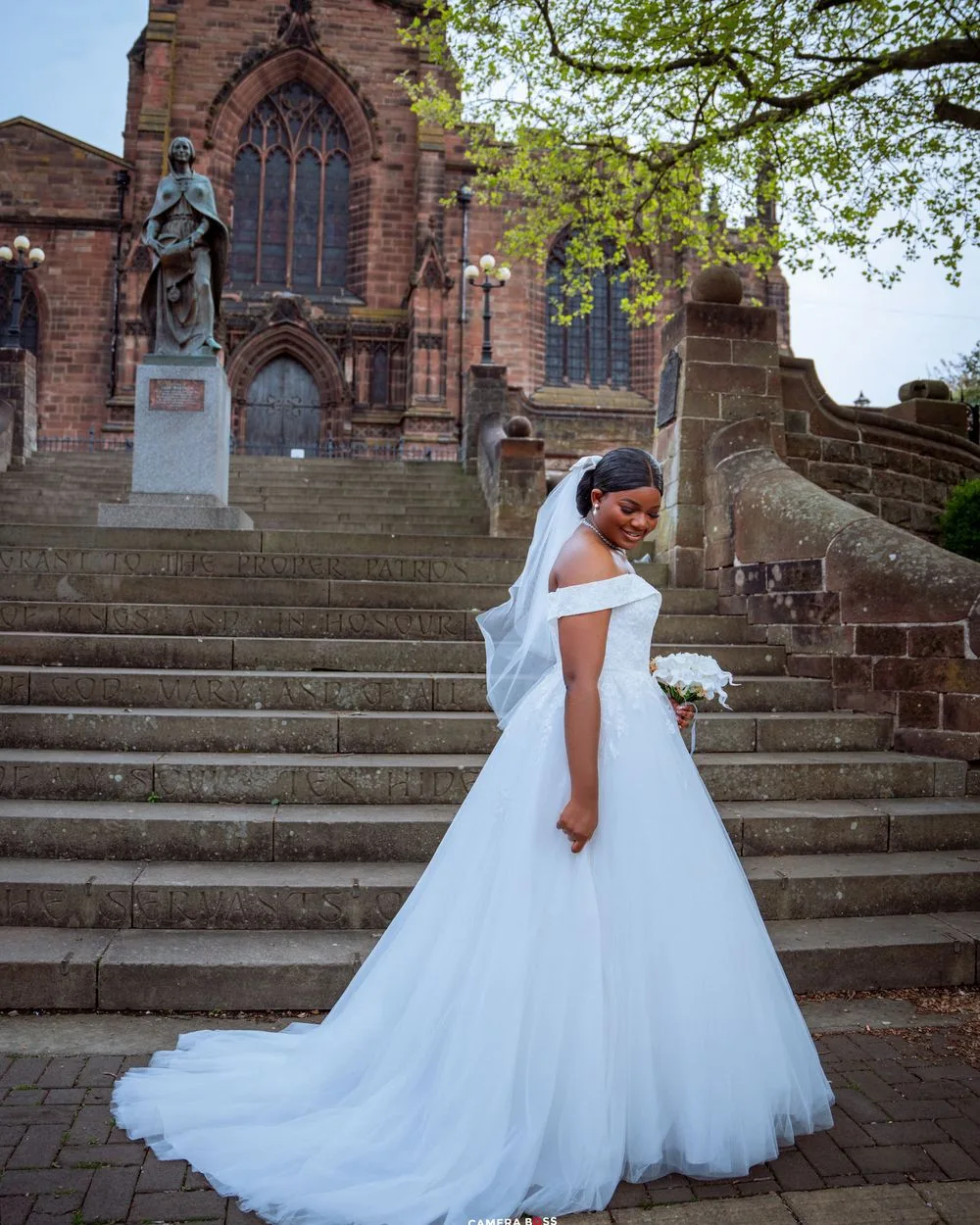 A stunning white ball gown wedding dress with a long train photographed on historic church steps.