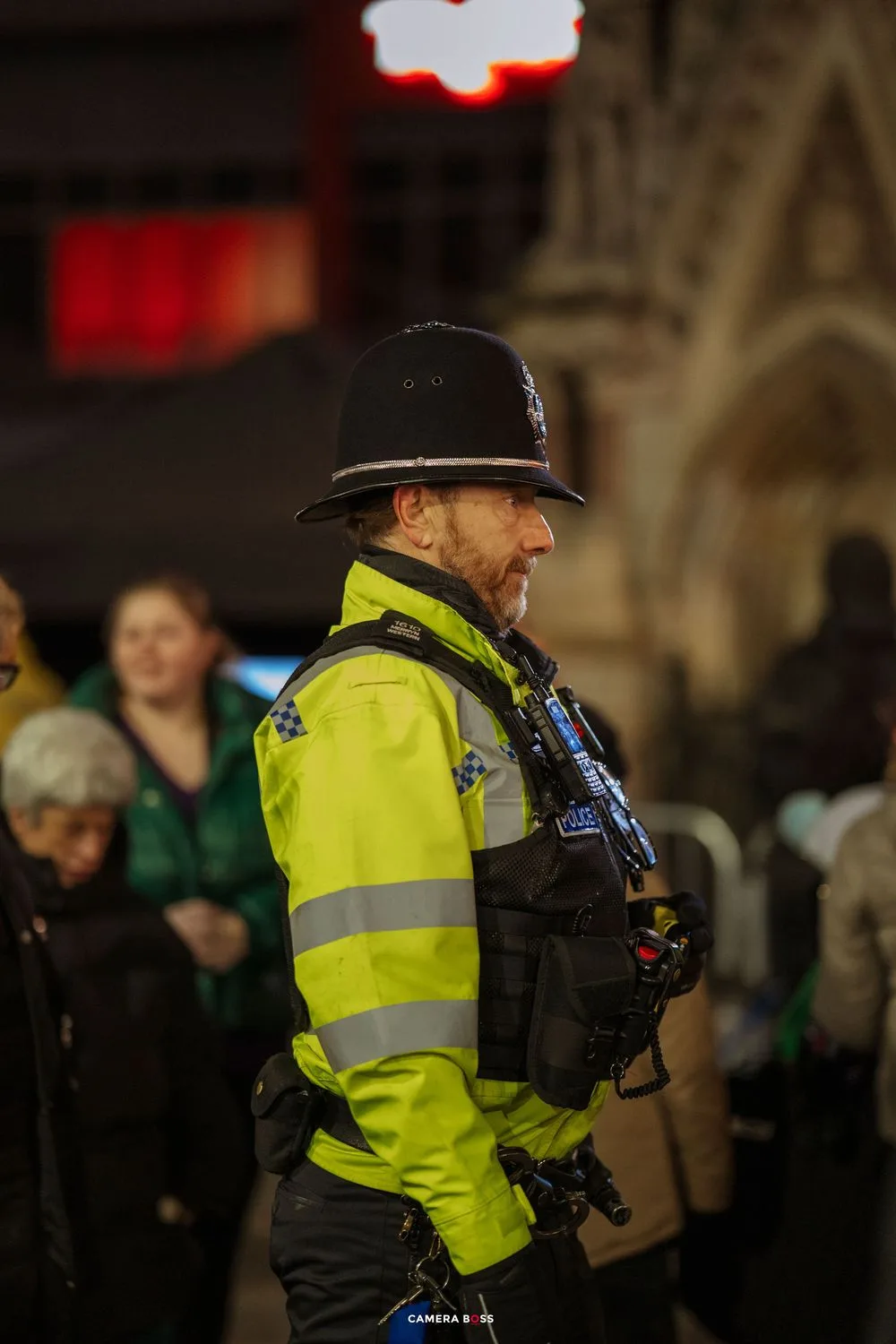 Police officer in high-visibility vest patrols a crowded nighttime event.