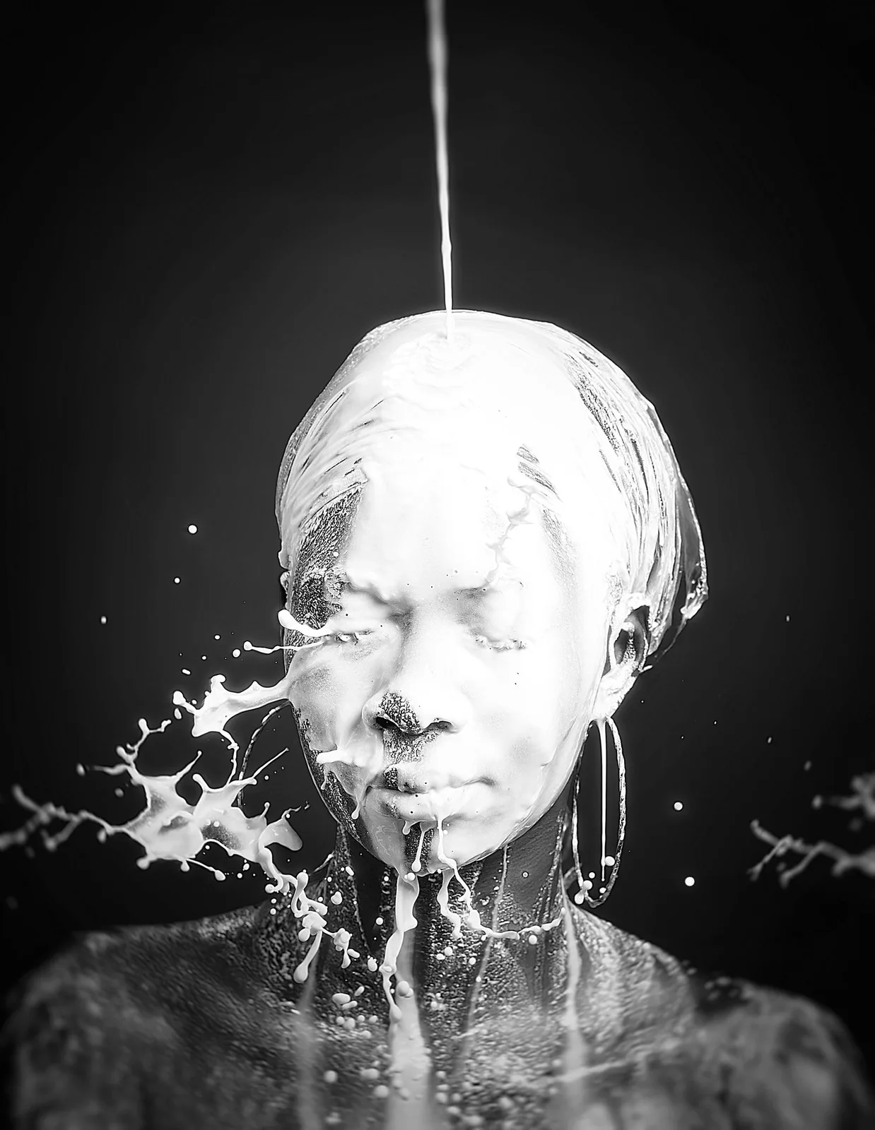 Artistic black and white portrait with milk or white liquid splashing and dripping onto a figure from above.