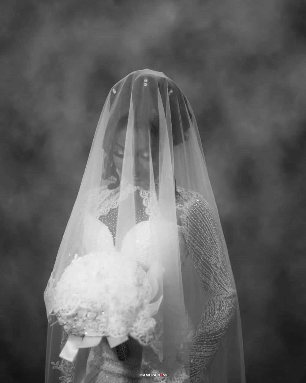 A delicate white bridal veil with lace detailing flows elegantly in black and white photography.