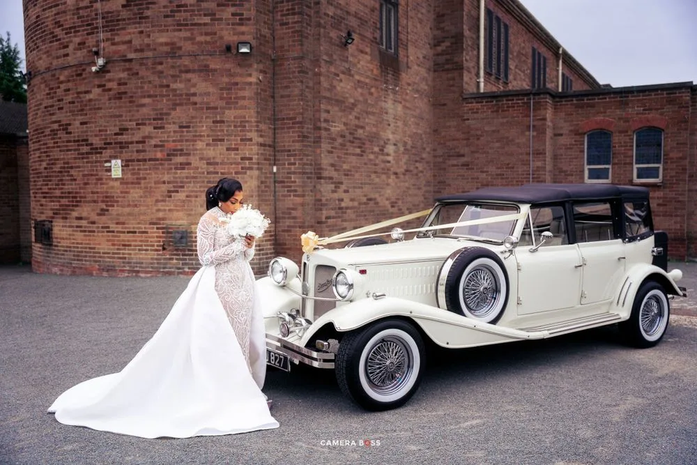 A classic white vintage Rolls Royce wedding car parked outside a brick building.