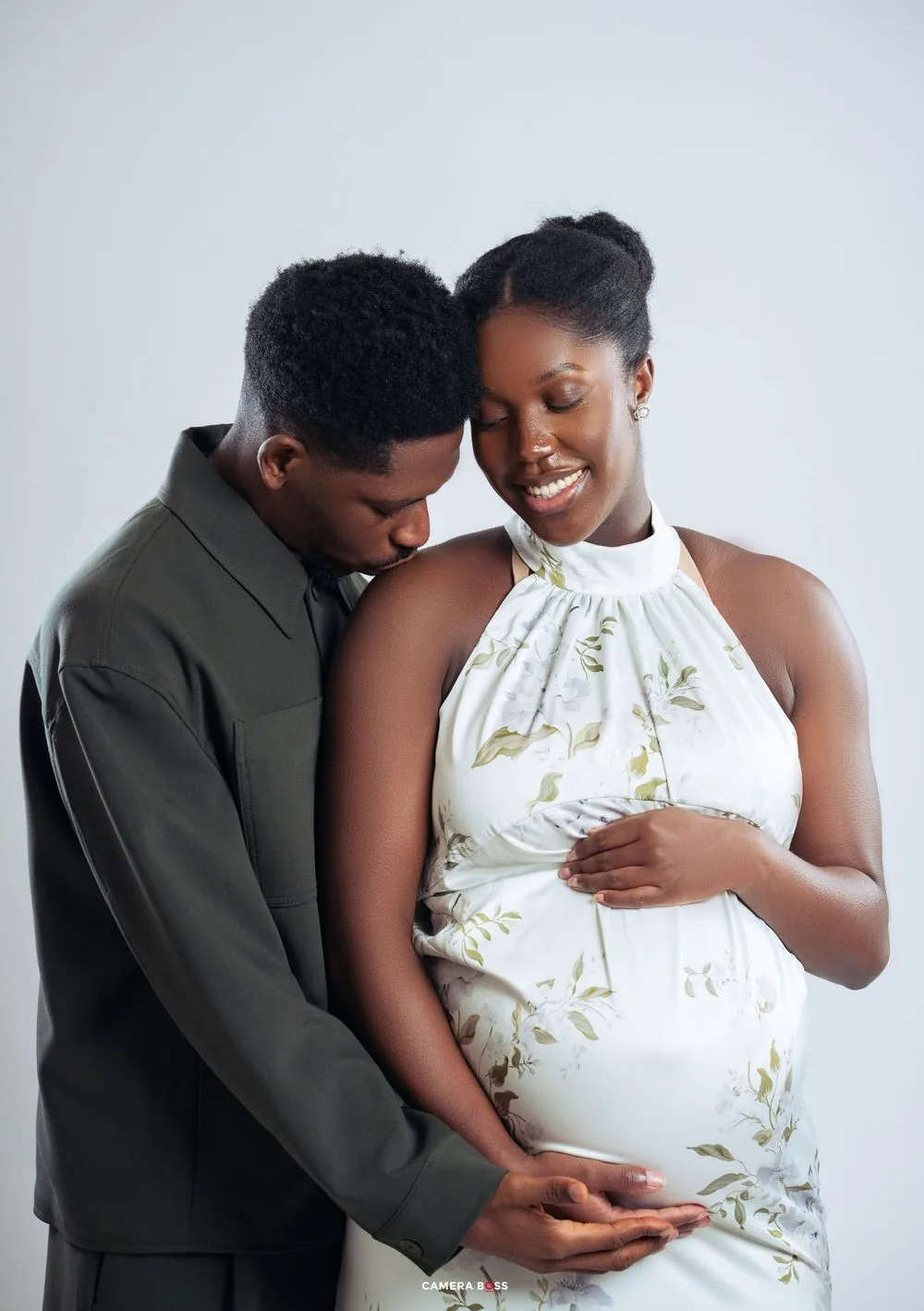 Beautiful maternity portrait in soft lighting showing tenderness as couple shares intimate moment with hands on pregnant belly.