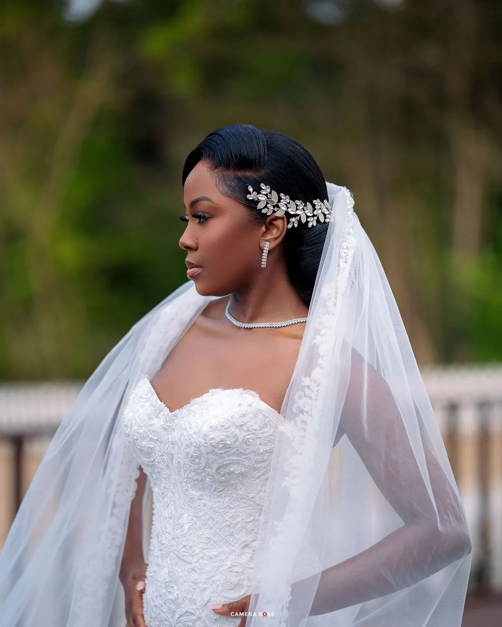 A beautiful bride poses in a strapless white wedding gown with a flowing veil and crystal hair accessories.