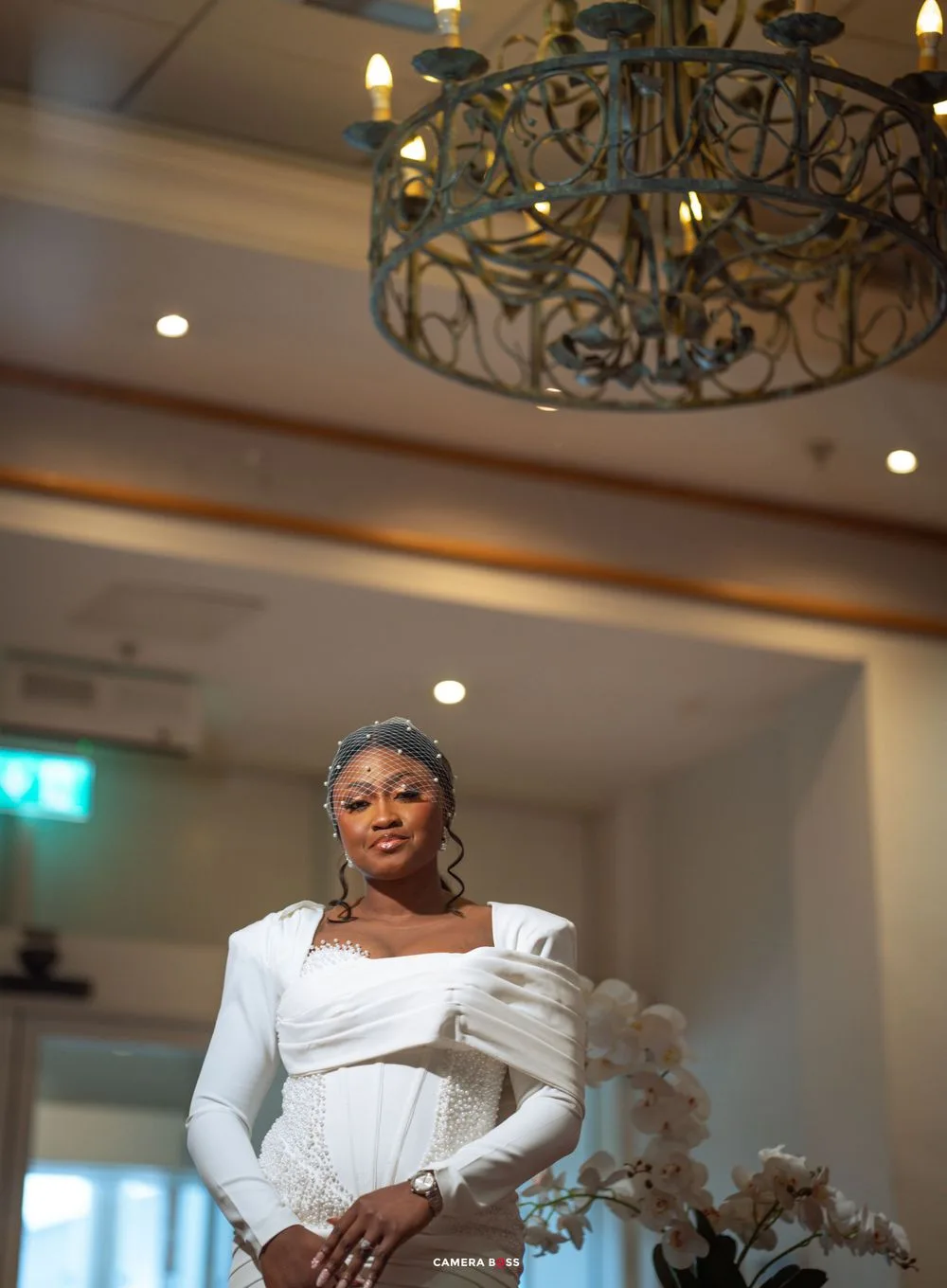 Elegant bridal portrait with ornate chandelier and soft lighting in a luxurious indoor venue.
