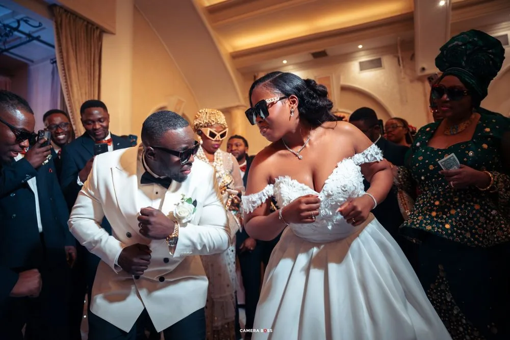 Dancing couple shares a joyful moment at their wedding reception surrounded by guests.