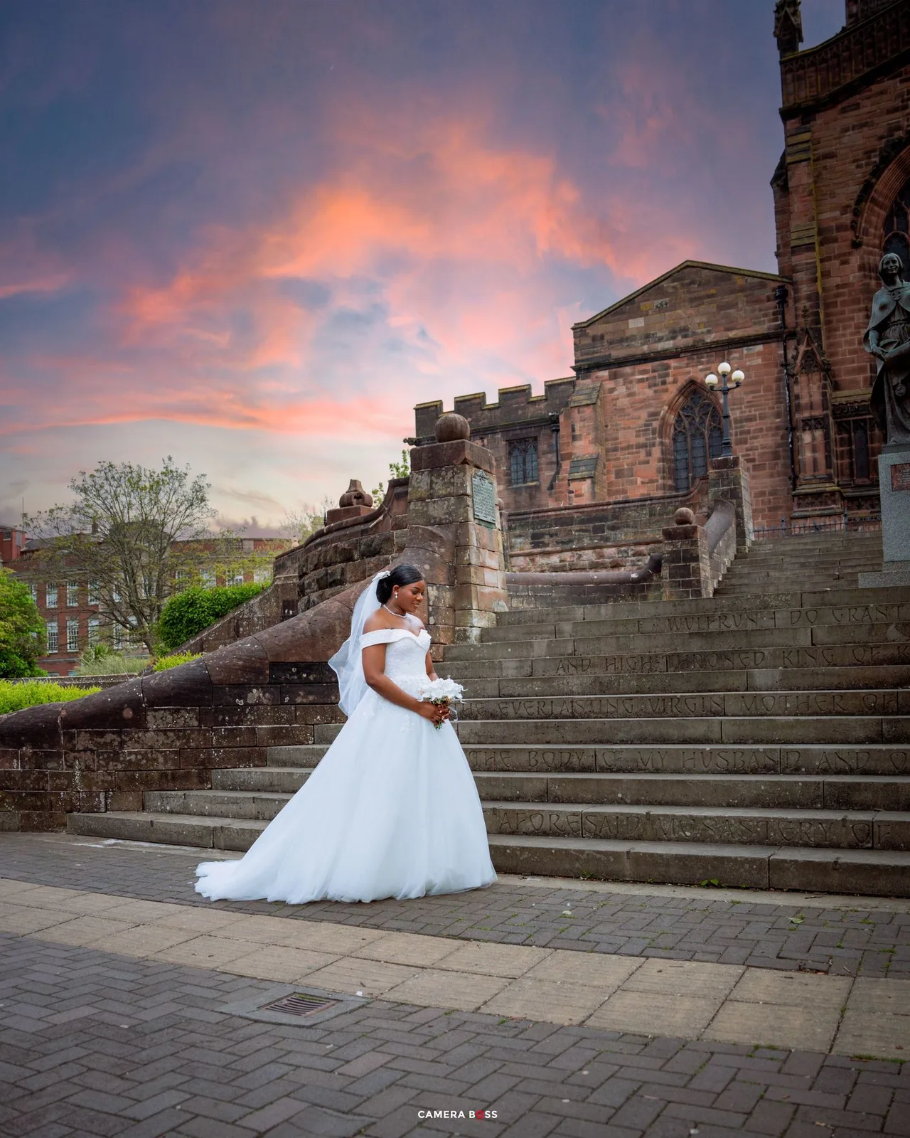 Beautiful wedding photo featuring a bride in a white gown on grand stone steps of a historic cathedral at sunset.