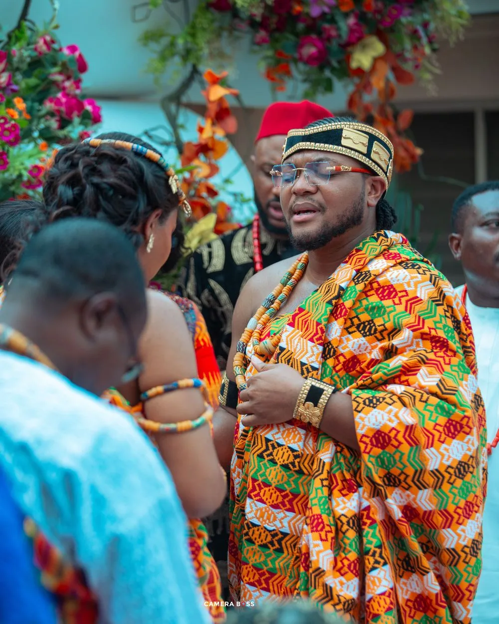 Traditional African celebration with people wearing vibrant patterned clothing and cultural attire at a festive gathering.
