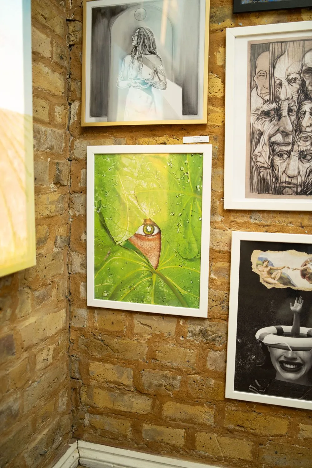 Gallery installation view at Boomer Gallery London showing mixed media artworks and photography including Cameraboss work on exposed brick wall