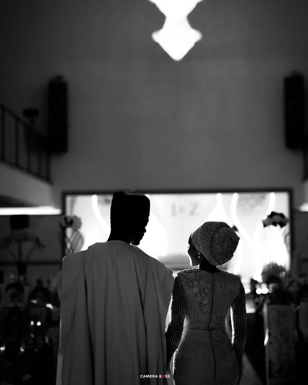 Silhouettes of people standing in dark lighting create a dramatic contrast against a bright background.