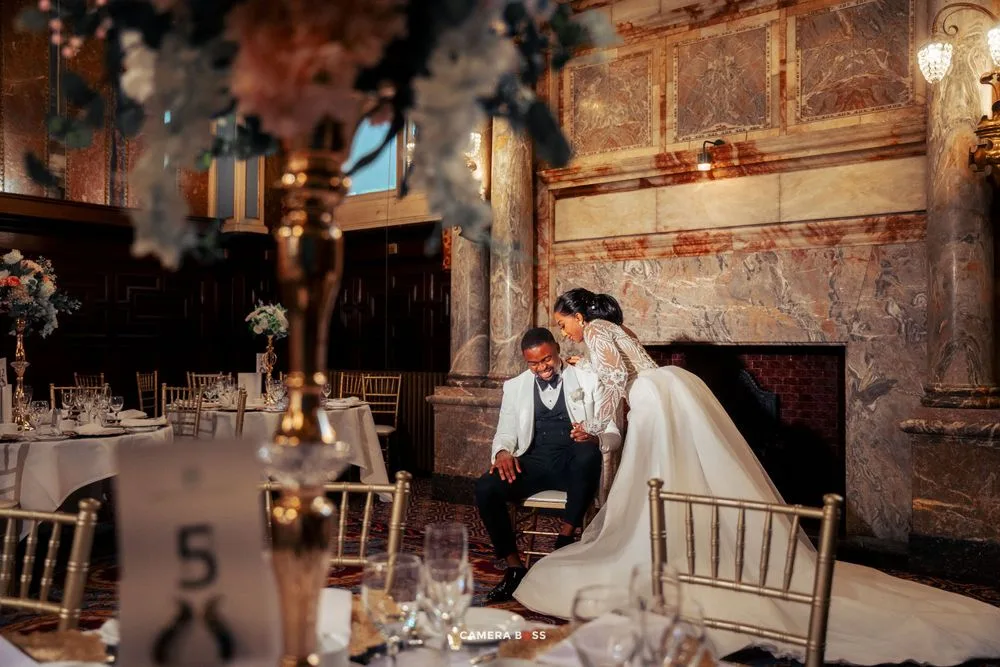 A romantic wedding reception scene in an elegant vintage venue with ornate walls and table settings.