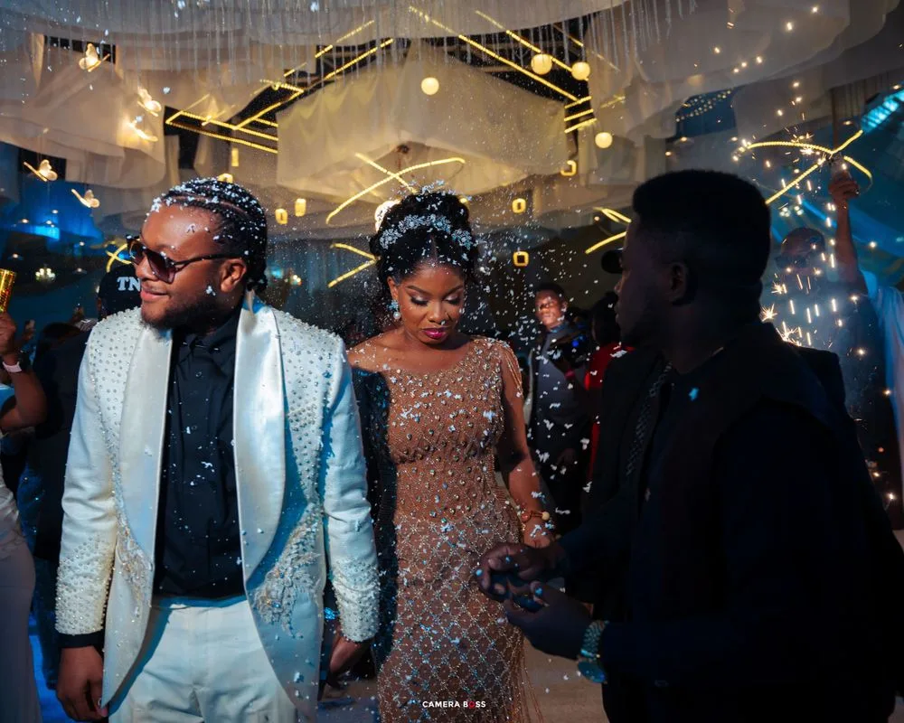 Partygoers dance under sparkling lights and confetti at a glamorous nighttime celebration with festive decorations.