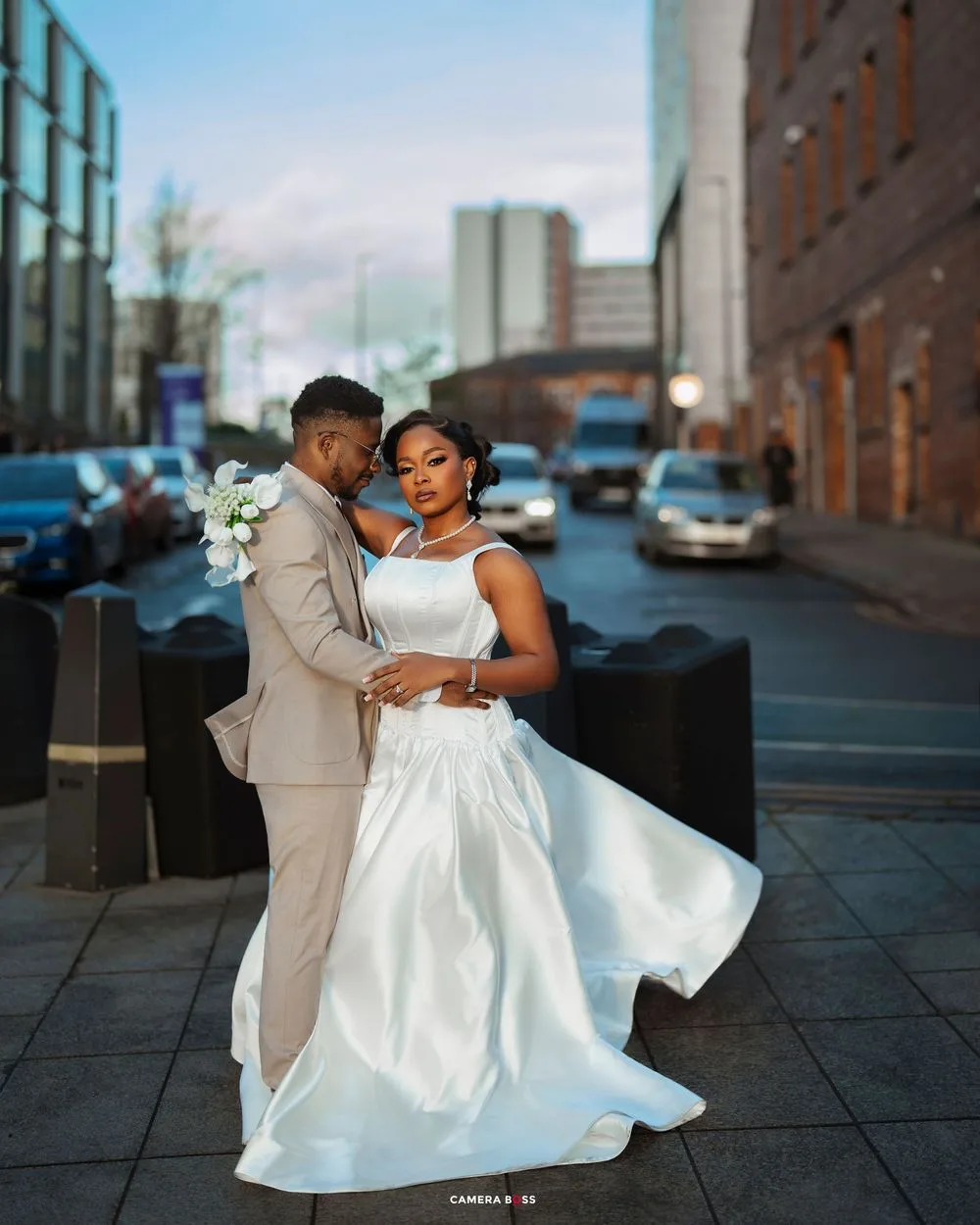 A couple dances together outdoors, with the bride's white dress flowing elegantly against an urban backdrop.