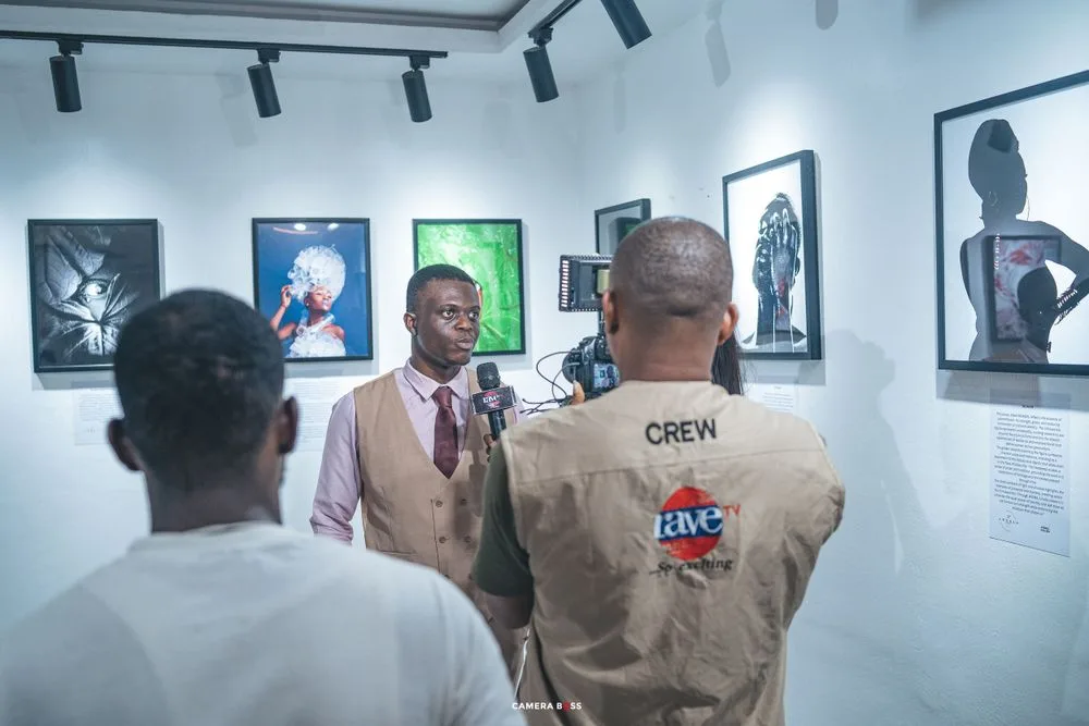 People observe and discuss artwork displayed at a gallery exhibition with colorful framed portraits on white walls.