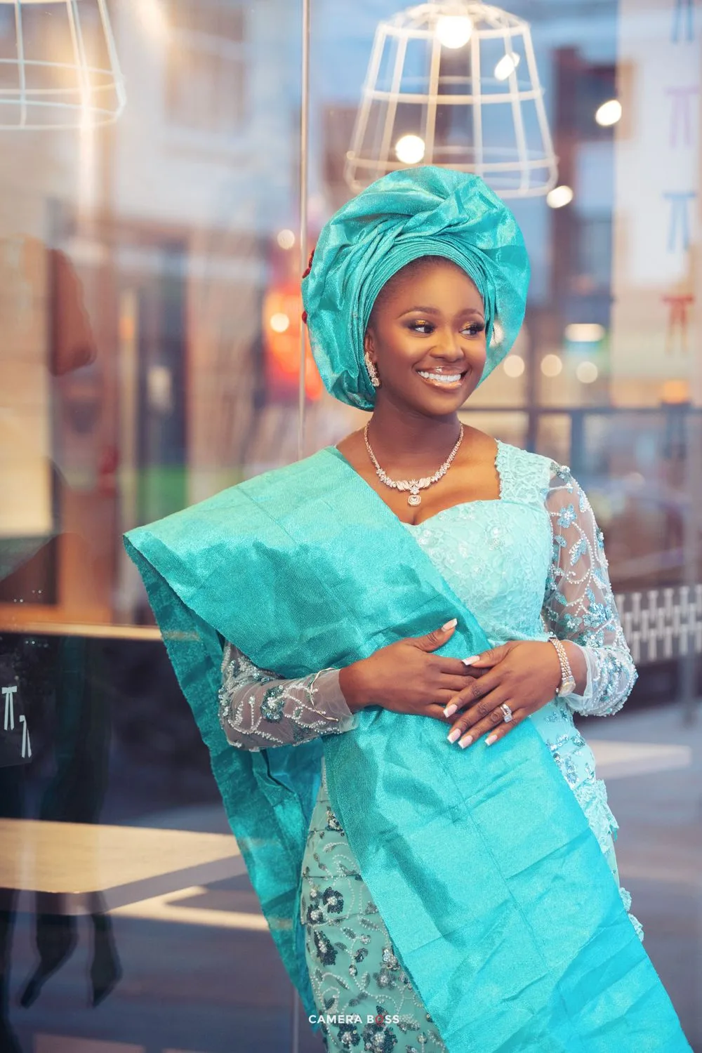 Beautiful traditional Nigerian attire in turquoise featuring a lace dress, gele headwrap and matching accessories.