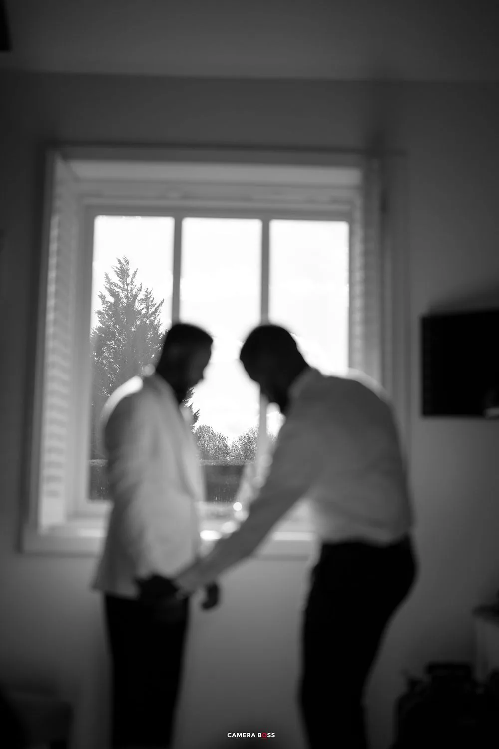 Blurry black and white sequence of people moving near a window in what appears to be an office setting.