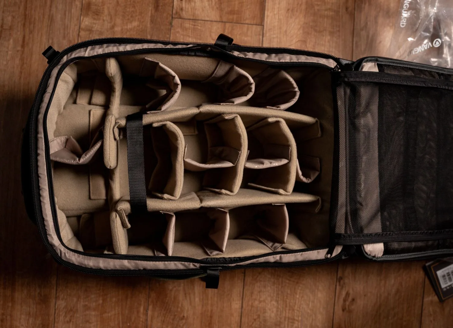 Overhead view of an open black camera bag with padded beige dividers creating organized compartments for equipment storage.